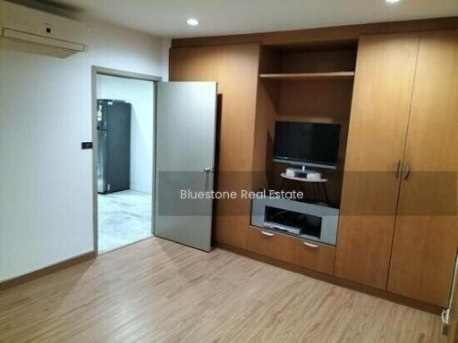 A minimalist living area with built-in wooden cabinets and a television.