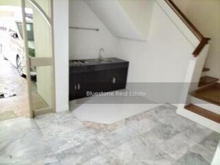 Small area under stairs with a sink and cabinetry