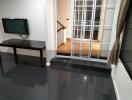 Modern living room with flat-screen TV and glass door opening to a hallway