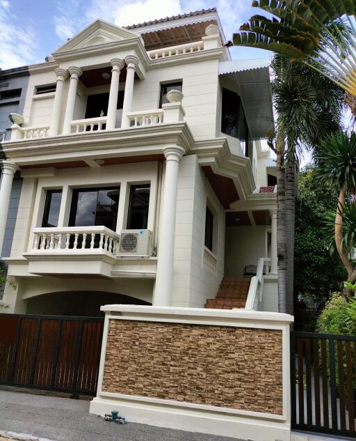 Three-story residential building with classical architectural elements and greenery