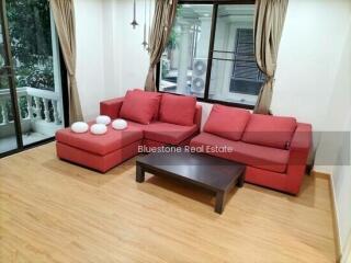 Spacious living room with red sofas and hardwood flooring