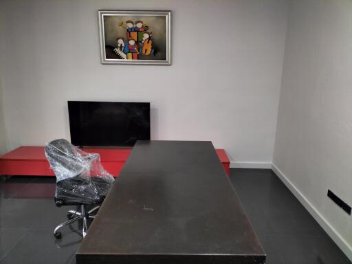 Modern office space with desk, chair, TV, and art piece on the wall