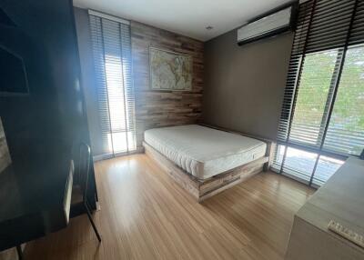 Modern bedroom with wooden flooring, large windows, and an air conditioning unit