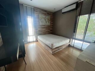 Modern bedroom with wooden flooring, large windows, and an air conditioning unit