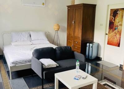 A well-furnished bedroom with a bed, wardrobe, sofa, coffee table, air conditioning, and decorative items.