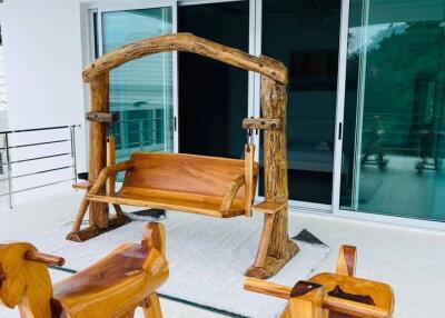 A balcony with wooden swing and rocking chairs
