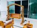 A balcony with wooden swing and rocking chairs