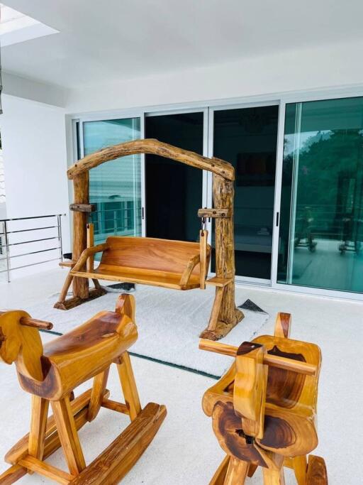 A balcony with wooden swing and rocking chairs