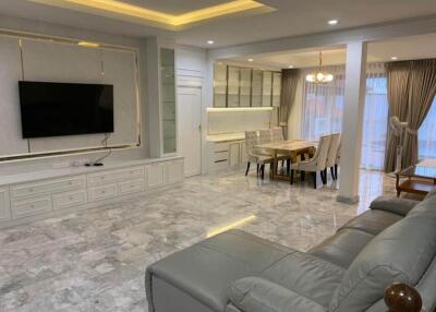 Modern living room with TV, dining area, and marble flooring