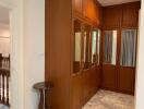 Closet area with wooden cabinets and mirrors