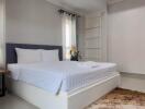 Well-lit modern bedroom with a neatly made bed and a soft rug