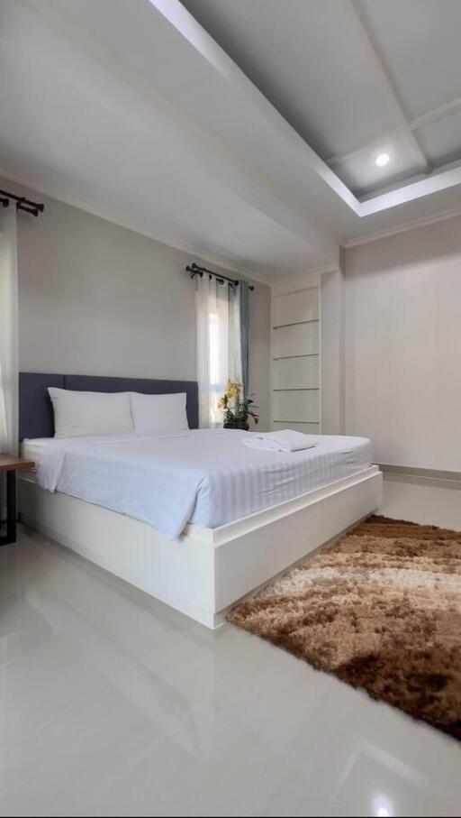 Well-lit modern bedroom with a neatly made bed and a soft rug