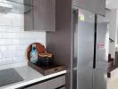 Modern kitchen with gray cabinets, white countertops, built-in oven, and double-door refrigerator