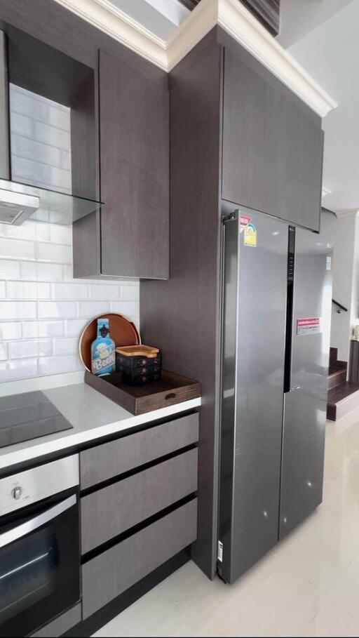 Modern kitchen with gray cabinets, white countertops, built-in oven, and double-door refrigerator