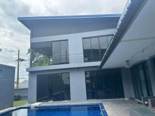 Modern two-story house with large windows and a swimming pool