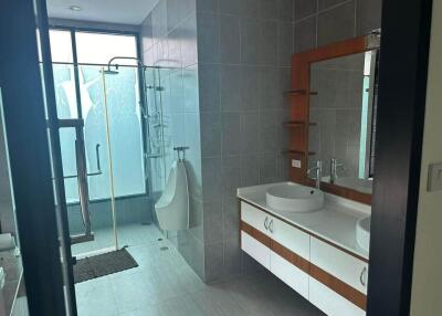 Modern bathroom with a large glass window, spacious shower, and dual sinks with a mirror