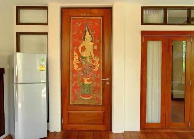 A kitchen area with a refrigerator and a decorative wooden door