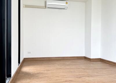 A spacious, unfurnished room with wooden flooring and large windows