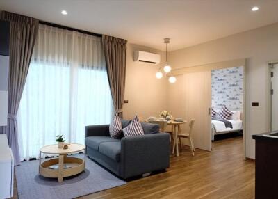 Spacious living room with modern decor, adjoining dining area, and bedroom