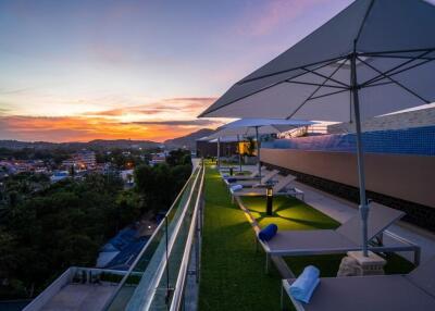 Rooftop patio with lounge chairs, umbrellas, and sunset view