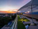 Rooftop patio with lounge chairs, umbrellas, and sunset view
