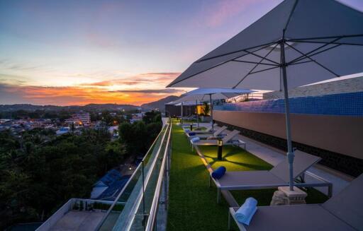 Rooftop patio with lounge chairs, umbrellas, and sunset view