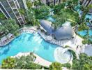 Aerial view of a modern apartment complex with swimming pools and lush gardens