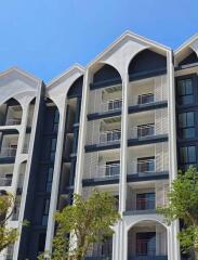 Modern multi-story residential building with balconies and trees