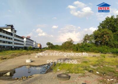Vacant land with some vegetation and nearby buildings