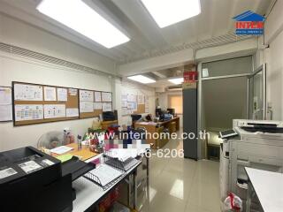 Business office with desks, chairs, printers, and documents on the wall