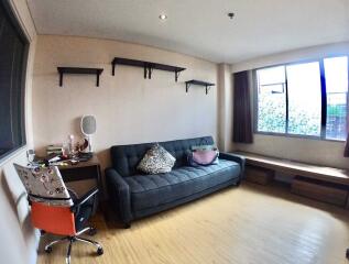 Well-lit living room with couch, desk, and shelves