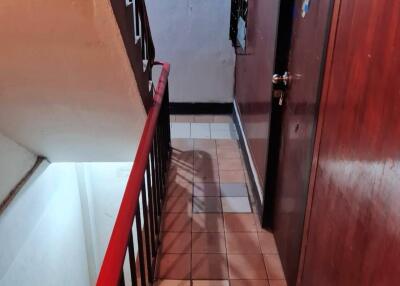 Stairway with red railing and tiled floor