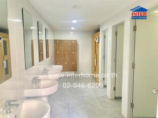 Clean bathroom area with sinks, mirrors, and wooden storage lockers