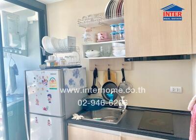 Small modern kitchen with a refrigerator, sink, and hanging utensils