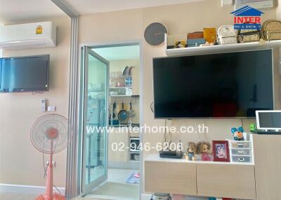 Living room with wall-mounted TV and storage, adjacent to a kitchen