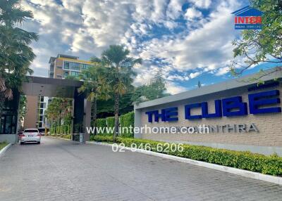 Entrance to The Cube condominium with visible signage and surrounding landscape