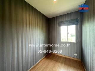 Empty bedroom with wooden floor and striped wallpaper