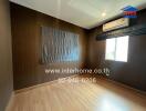 Empty bedroom with wooden floor, air conditioner, and window