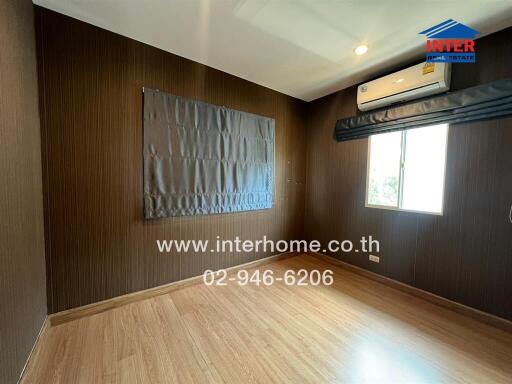 Empty bedroom with wooden floor, air conditioner, and window