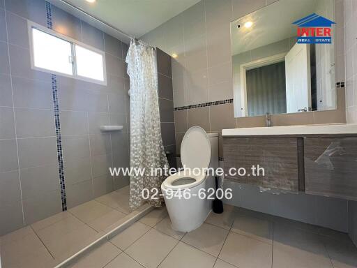 Modern bathroom with shower, toilet, vanity, and large mirror