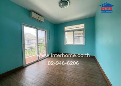 Vacant bedroom with wooden floor, blue walls, large windows, and balcony access