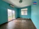 Vacant bedroom with wooden floor, blue walls, large windows, and balcony access