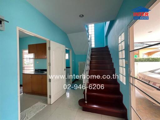 Interior view of house with staircase, kitchen, and door leading outside