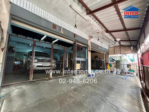 A garage with a parked vehicle and an open gate