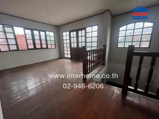 Interior view of a spacious room with wooden flooring and large windows