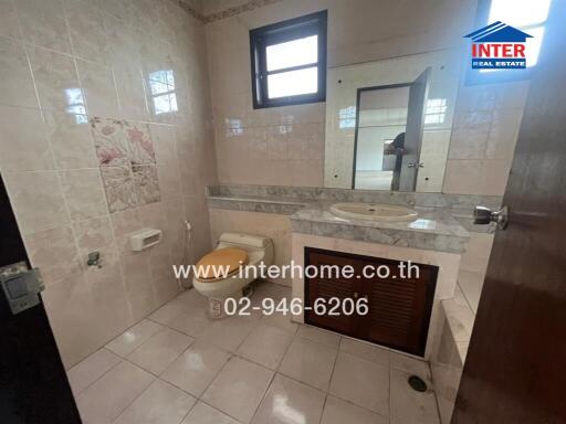 Bathroom with tiled walls and floor, a window, a toilet, a sink with a marble countertop, and a mirror.