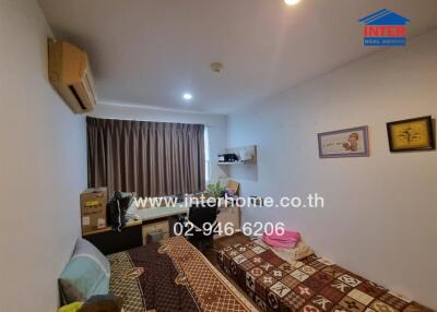 Bedroom with twin beds, patterned bedding, air conditioning, and window with brown curtains