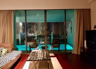 Spacious living room with large glass doors leading to a balcony with a pool view
