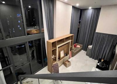 Modern living room with large windows, wooden shelving, and gray curtains