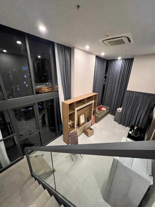 Modern living room with large windows, wooden shelving, and gray curtains